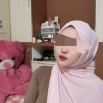 Woman in hijab with pink teddy bear.