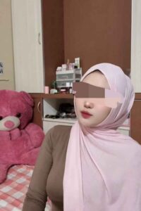 Woman in hijab with pink teddy bear.
